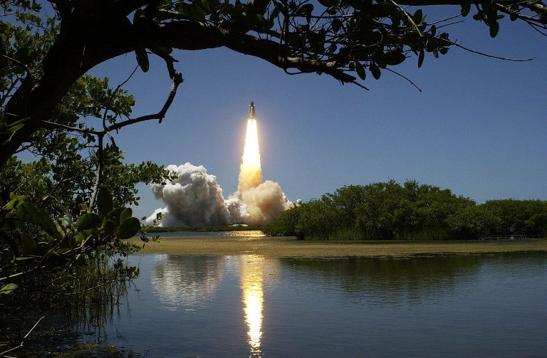 Trees and lake with distant rocket launch