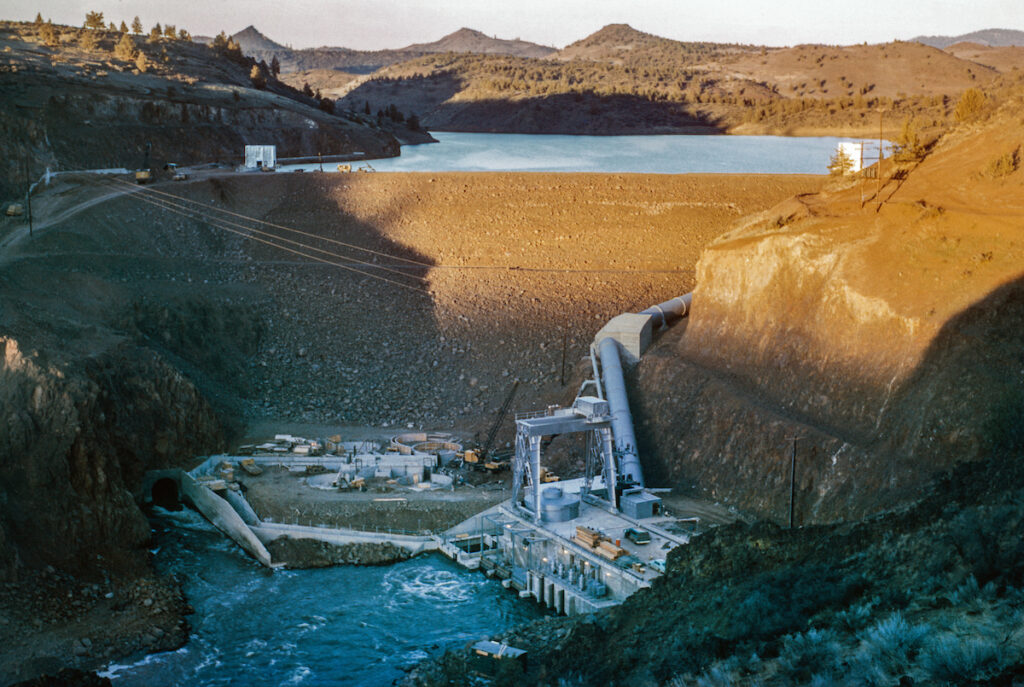Photo of earthen dam with reservoir in background.